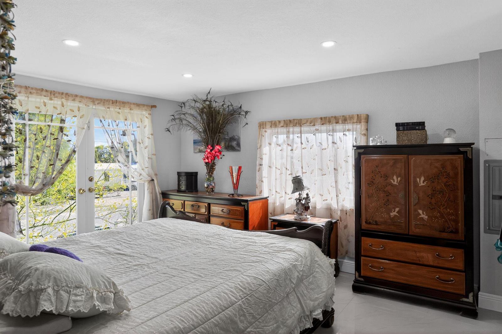 A bedroom features a bed, a large wooden armoire, a dresser, and glass doors to outside — 27910 Porgie Path, FL 33042, FL
