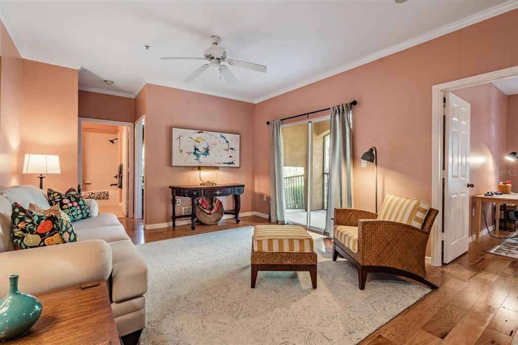 A living room features peach walls, a beige sofa, wicker armchair, and sliding glass doors — 10103 COURTNEY OAKS CIRCLE UNIT 103, TAMPA, FL