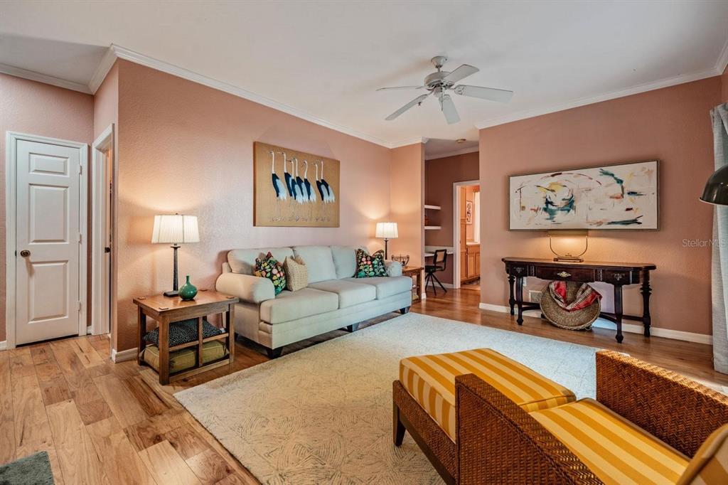 A living room features a beige sofa, striped ottoman, and artwork on peach-colored walls — 10103 COURTNEY OAKS CIRCLE UNIT 103, TAMPA, FL