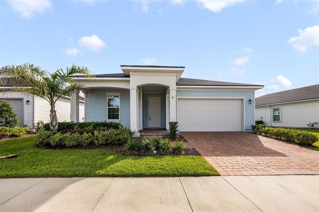 A single-story house with light blue siding, a brick paver driveway, and a palm tree — 6 FALMOUTH DRIVE, PALM COAST, FL