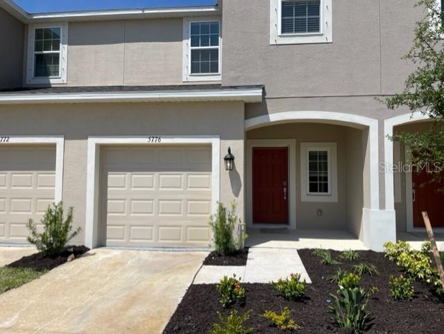 The exterior of a two-story townhouse features a tan facade, a garage, and a red door — 5776 HAVEN TERRACE, NOKOMIS, FL