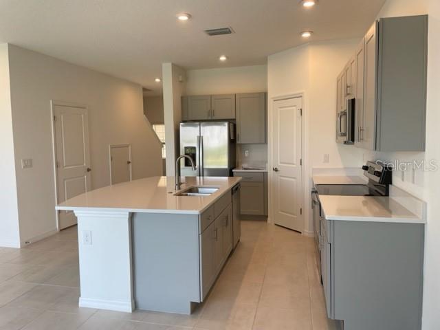 A kitchen features gray cabinets, white countertops, a center island, and stainless steel appliances — 5776 HAVEN TERRACE, NOKOMIS, FL