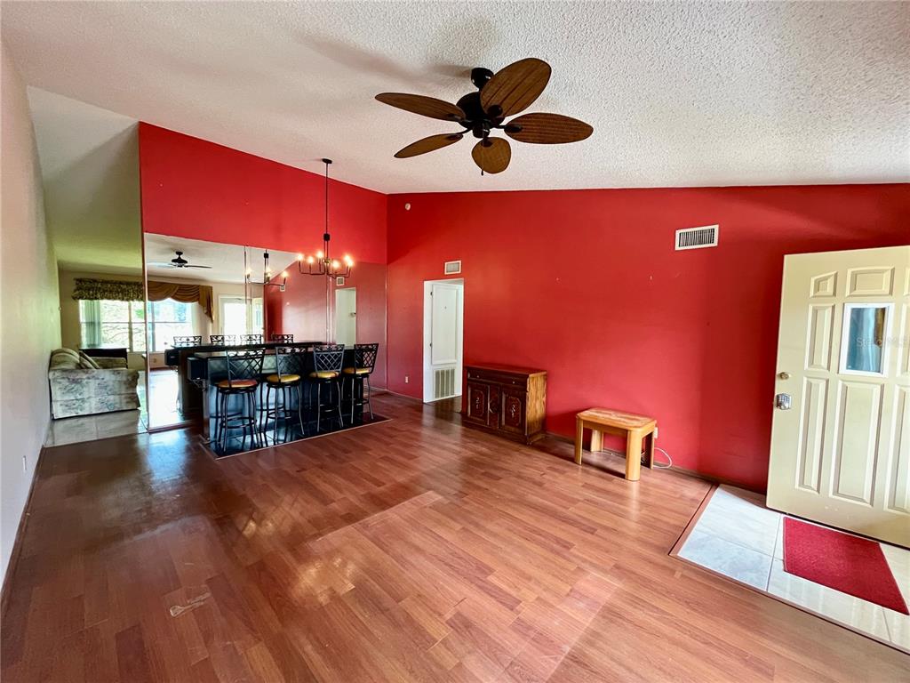 A living room with red walls, wood flooring, a ceiling fan, and a built-in bar — 2220 SPANISH DRIVE UNIT 54, CLEARWATER, FL