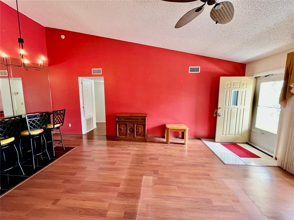 A room with red walls, wood-look flooring, a breakfast bar, and an exterior door — 2220 SPANISH DRIVE UNIT 54, CLEARWATER, FL
