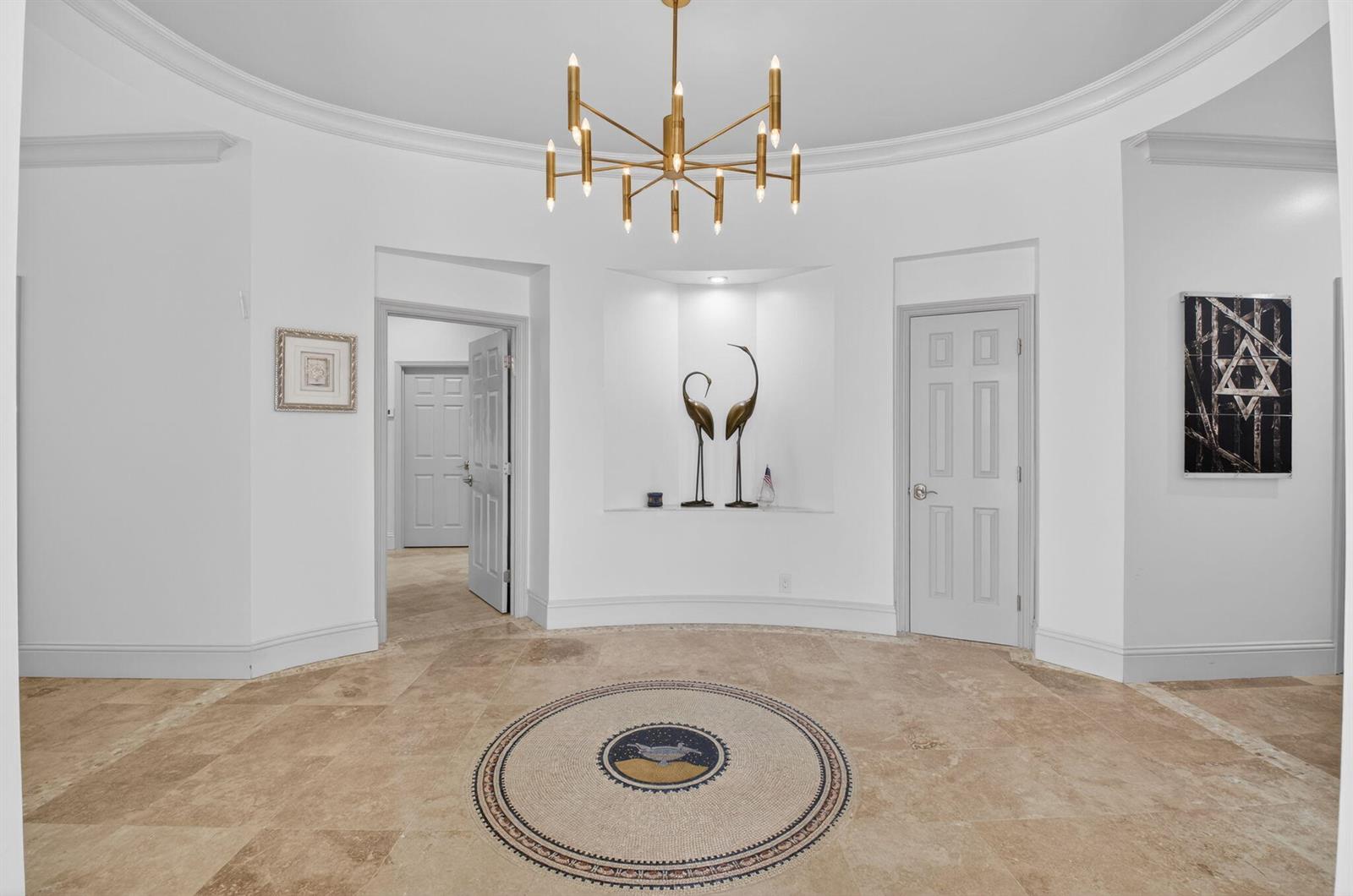 A circular foyer features stone tile flooring, a central mosaic medallion, and a gold chandelier — 21237 Harrow Court, Boca Raton FL 33433, BOCA RATON, FL