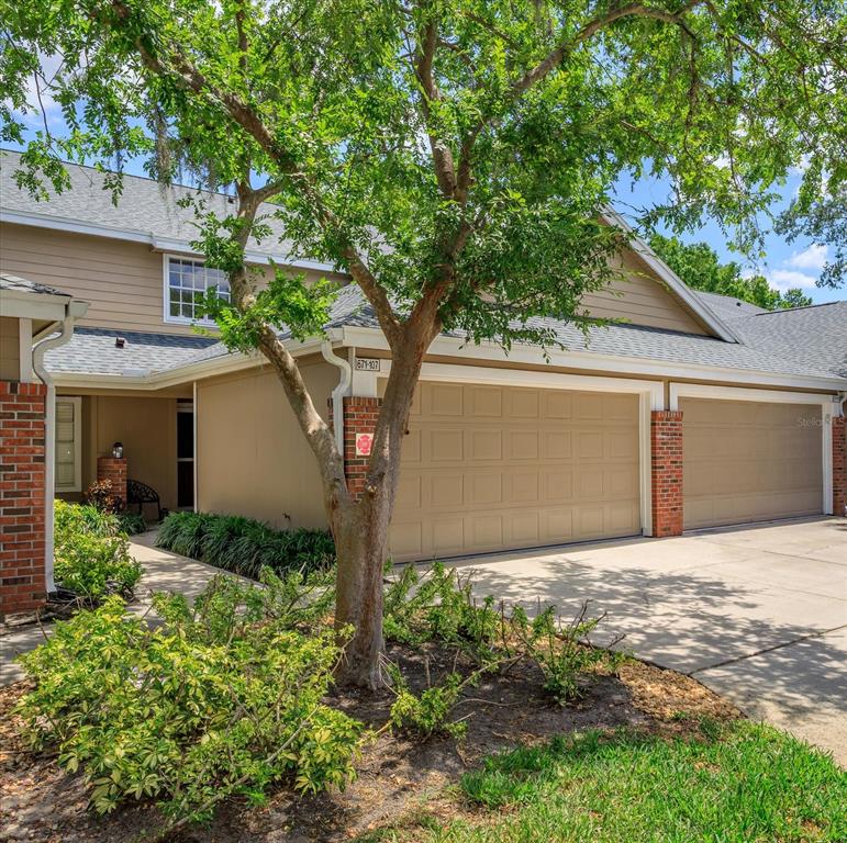 A tan two-story townhouse exterior features a two-car garage and a small front garden — 671 POST OAK CIRCLE UNIT 107, ALTAMONTE SPRINGS, FL
