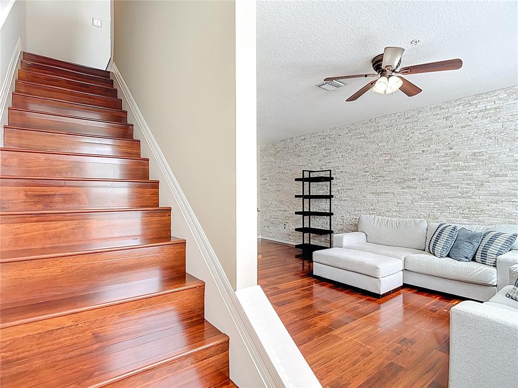 A staircase with dark wood steps leads to a living room with a stone wall — 3133 BAYSHORE OAKS DRIVE, TAMPA, FL