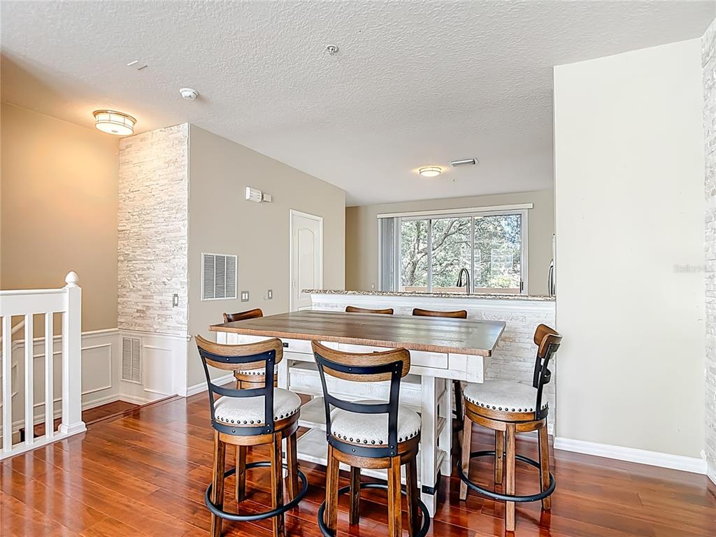 A dining area features a wooden table with four chairs and a stone-accented breakfast bar — 3133 BAYSHORE OAKS DRIVE, TAMPA, FL