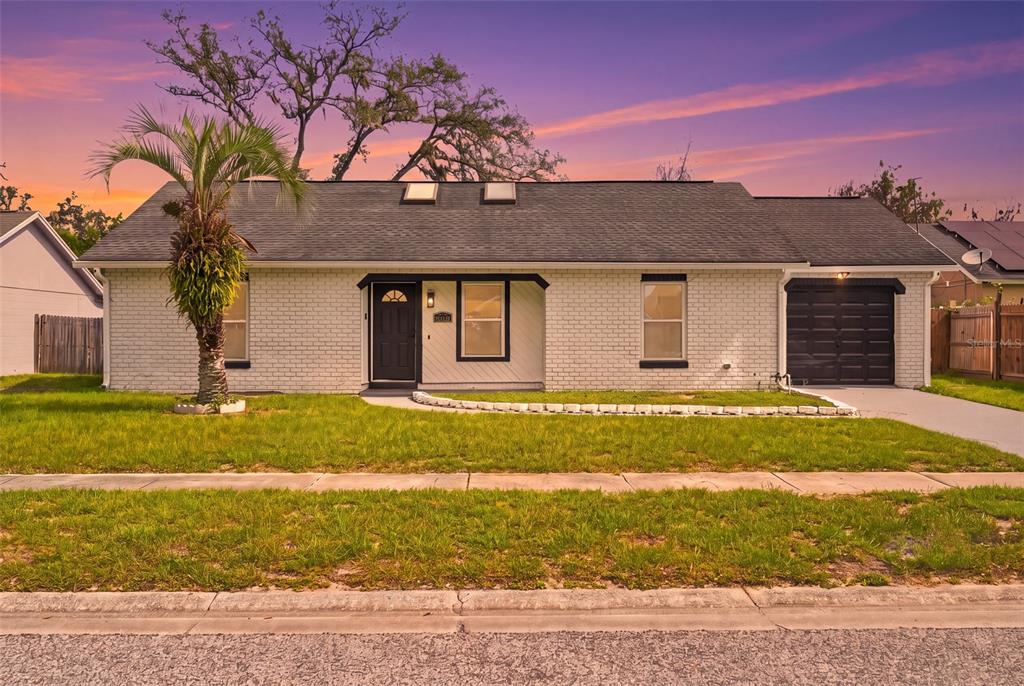 A single-story white brick house with a dark roof, black accents, and a front lawn — 6113 BEAUMONT AVENUE, ORLANDO, FL