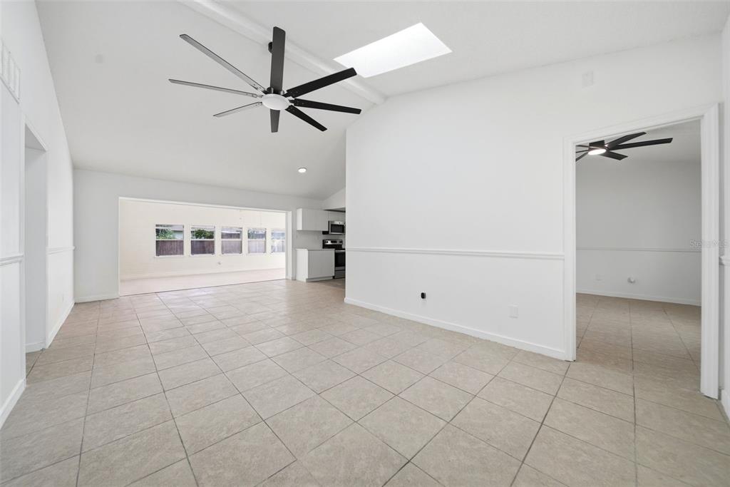 A bright, tiled living area features a vaulted ceiling, a large ceiling fan, and a skylight — 6113 BEAUMONT AVENUE, ORLANDO, FL