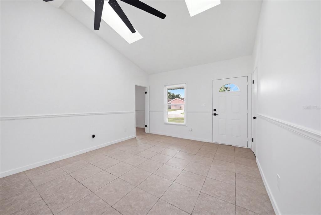 An empty room with white walls, tile flooring, a ceiling fan, and a front door — 6113 BEAUMONT AVENUE, ORLANDO, FL