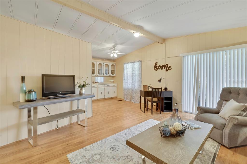 A living room features wood-look flooring, paneled walls, a television console, and a small desk — 57 N BOBWHITE ROAD, WILDWOOD, FL