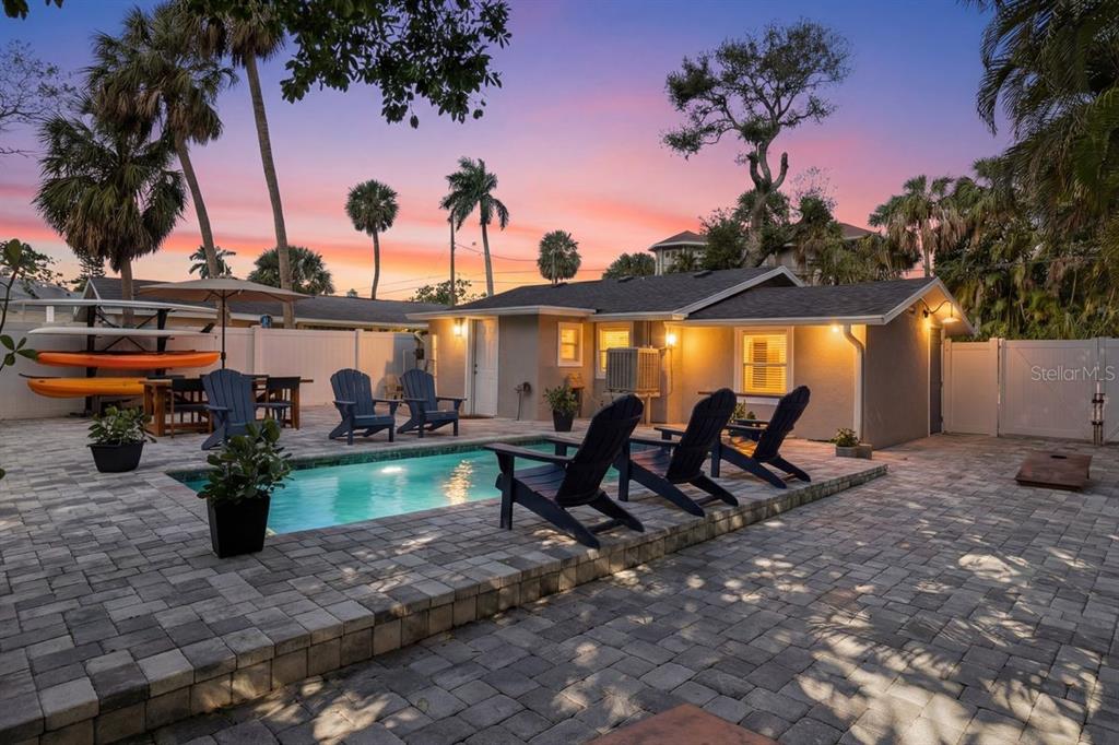 A backyard patio features a rectangular swimming pool, lounge chairs, and a small house exterior — 27 MICHIANA DRIVE, TERRA CEIA, FL