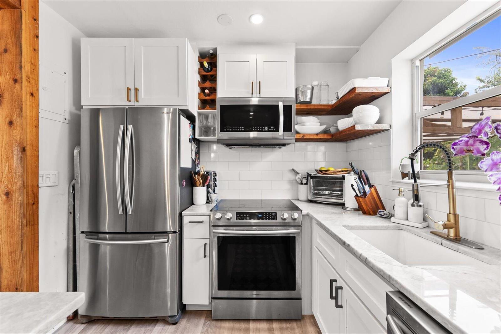 A kitchen features white cabinets, stainless steel appliances, marble countertops, and open wooden shelving — 350 Forest Hill Boulevard, West Palm Beach FL 33405, WEST PALM BEACH, FL