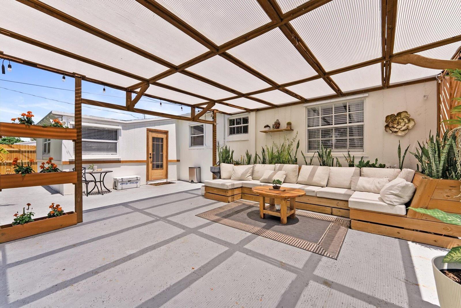 A covered outdoor patio features a large sectional sofa, a coffee table, and vertical planters — 350 Forest Hill Boulevard, West Palm Beach FL 33405, WEST PALM BEACH, FL