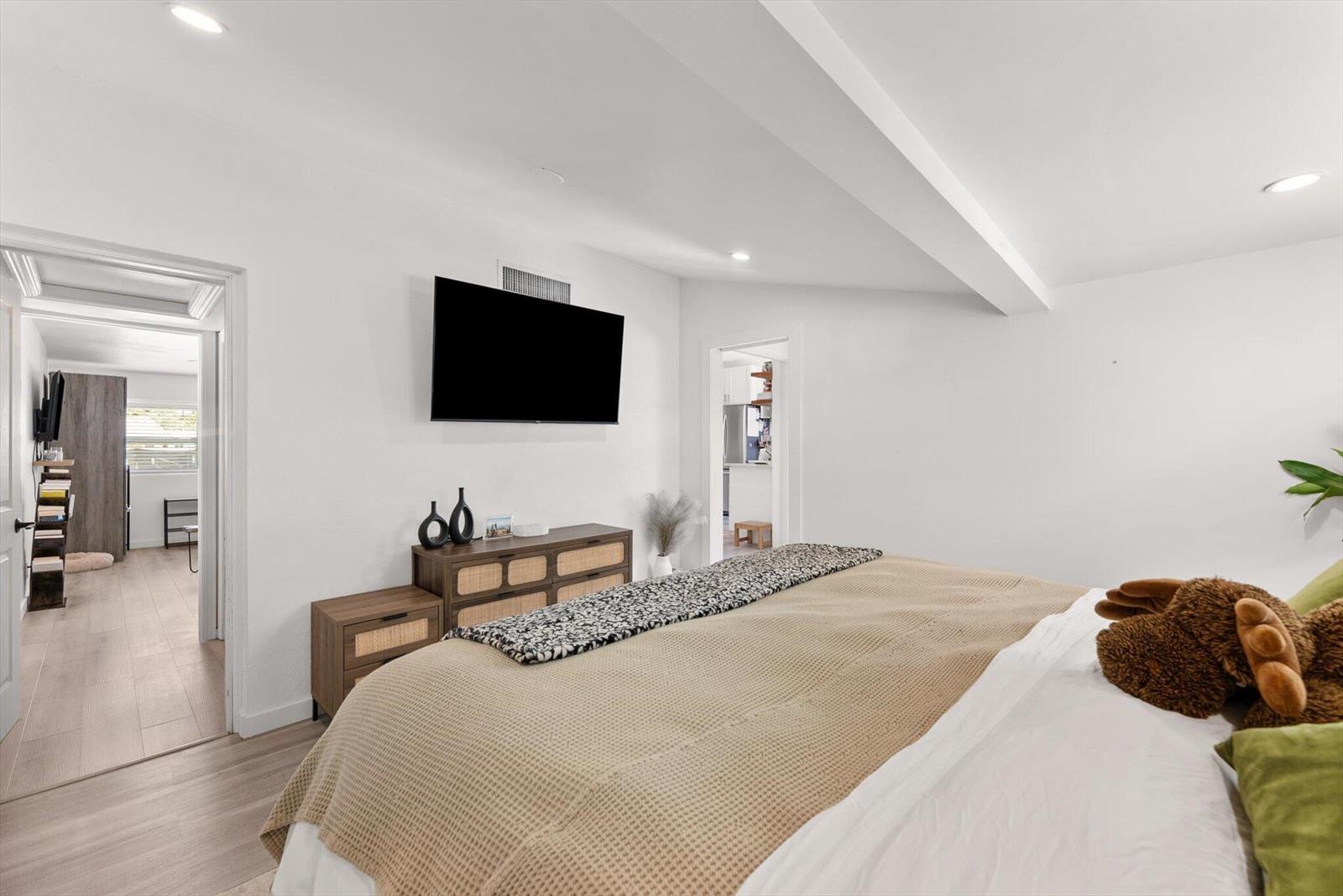 A bedroom features a bed, a wooden dresser with a television, and two doorways — 350 Forest Hill Boulevard, West Palm Beach FL 33405, WEST PALM BEACH, FL