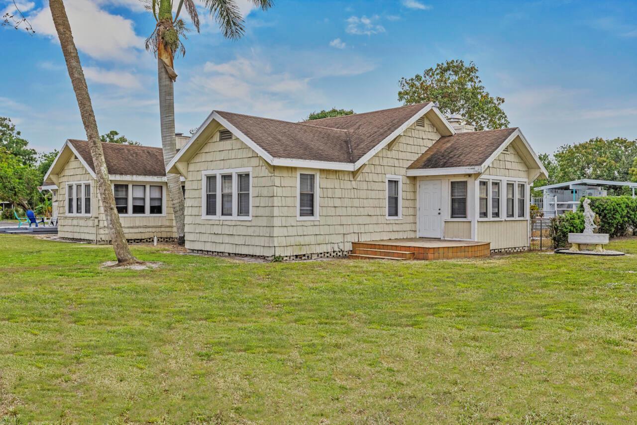 A light yellow, single-story house with shingle siding and a brown roof sits on grass — 14601 Orange Avenue, Fort Pierce FL 34945, FORT PIERCE, FL