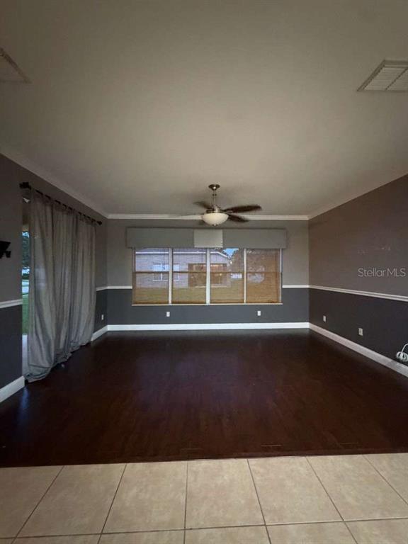 A living room features dark wood flooring, two-tone walls, a ceiling fan, and large windows — 1105 TOLUKE POINT, ORLANDO, FL