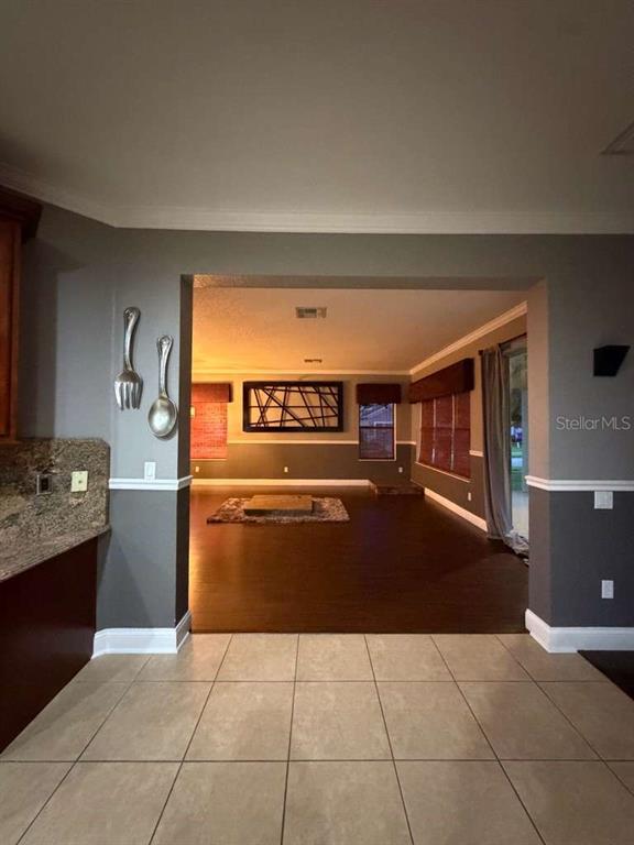 A view from a tiled kitchen into a living area with dark wood flooring — 1105 TOLUKE POINT, ORLANDO, FL