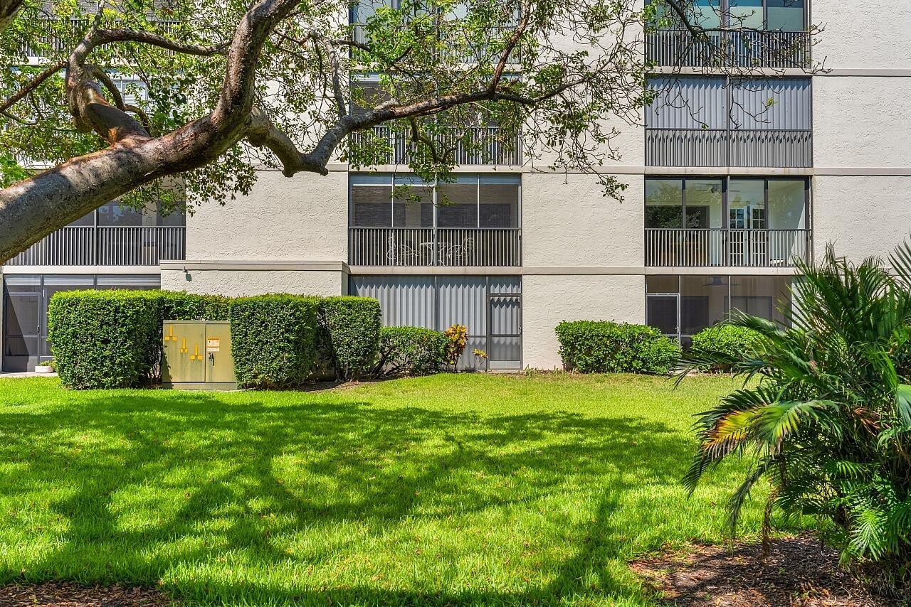 A multi-story apartment building with screened balconies overlooks a grassy lawn and landscaping — 300 N Highway A1a # 203c, Jupiter FL 33477, JUPITER, FL