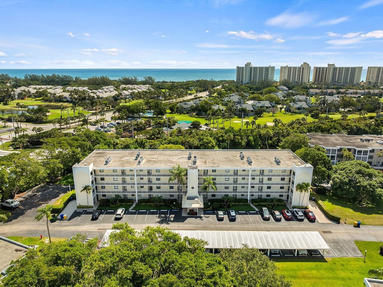 An aerial view shows a multi-story apartment building with a parking lot and surrounding greenery — 300 N Highway A1a # 203c, Jupiter FL 33477, JUPITER, FL