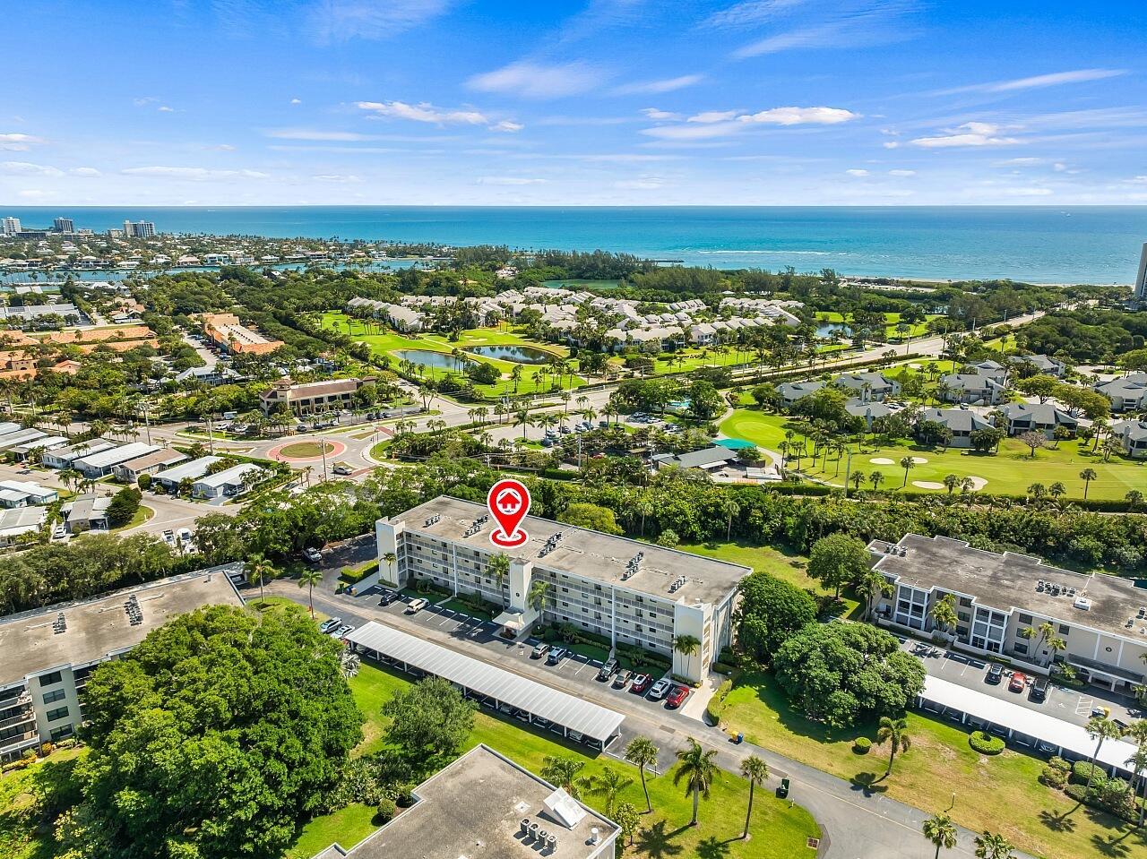An aerial view shows a multi-story apartment building surrounded by trees, parking, and a golf course — 300 N Highway A1a # 203c, Jupiter FL 33477, JUPITER, FL