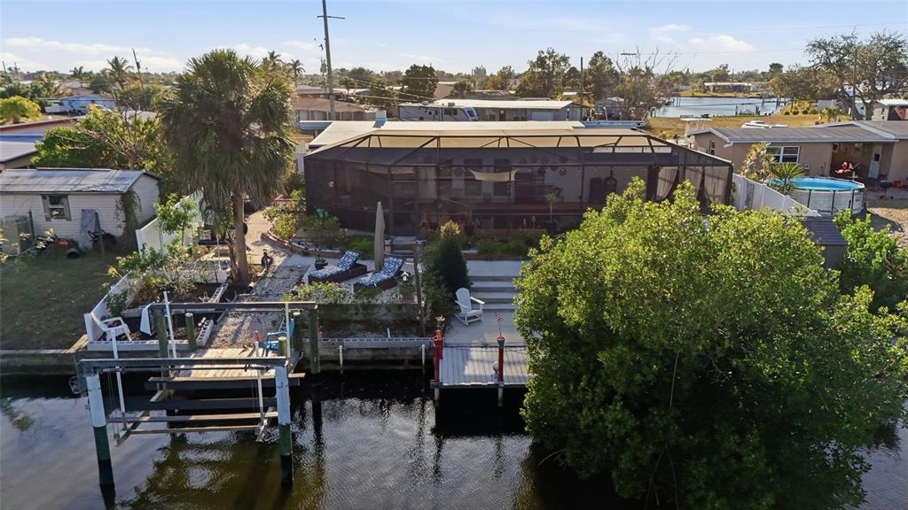 An aerial view of a waterfront house with a screened-in patio, dock, and boat lift — 4086 GARDNER DRIVE, PORT CHARLOTTE, FL