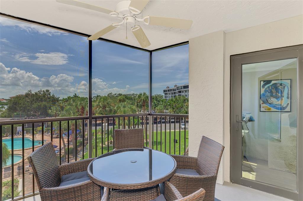 A screened-in balcony features a glass-topped table, wicker chairs, a ceiling fan, and pool views — 5855 MIDNIGHT PASS ROAD UNIT 333, SARASOTA, FL