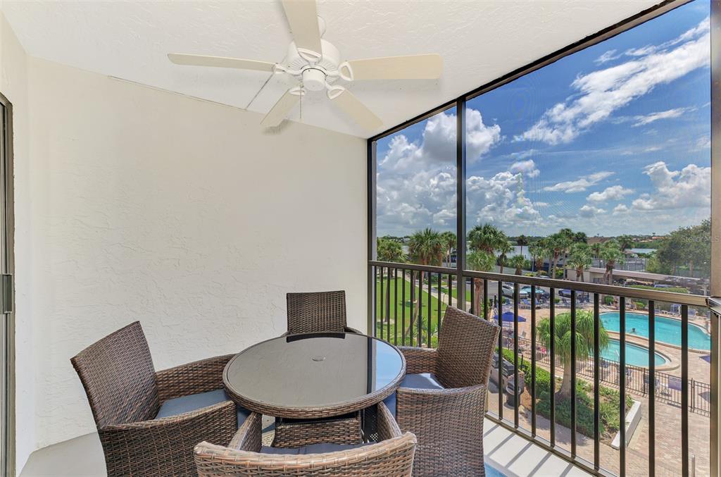A screened-in balcony features a glass-top table, four wicker chairs, a ceiling fan, and pool views — 5855 MIDNIGHT PASS ROAD UNIT 333, SARASOTA, FL