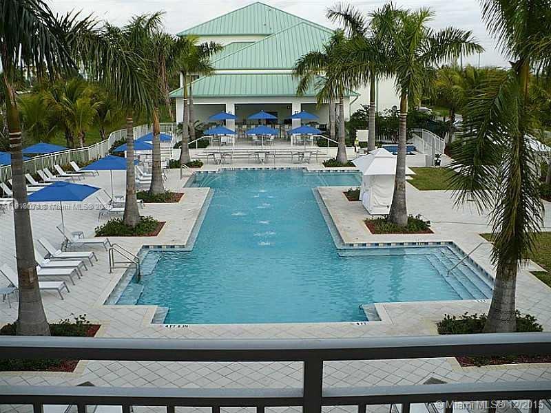 A swimming pool with fountains is surrounded by palm trees and a patio with umbrellas — 5300 NW 87th Ave # 802, Doral FL 33178, DORAL, FL