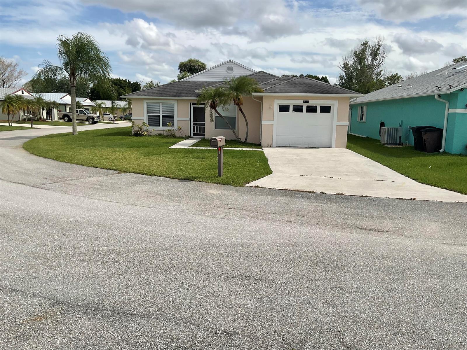 A single-story peach-colored house with a white garage door and a palm tree out front — 14151 Cisne Circle, Fort Pierce FL 34951, FORT PIERCE, FL