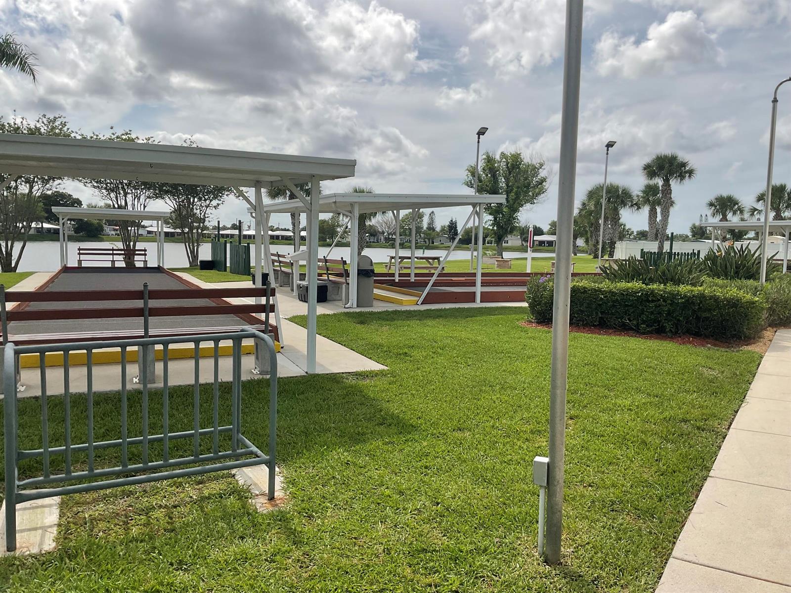 Outdoor shuffleboard courts with covered seating areas overlook a lake on a sunny day — 14151 Cisne Circle, Fort Pierce FL 34951, FORT PIERCE, FL