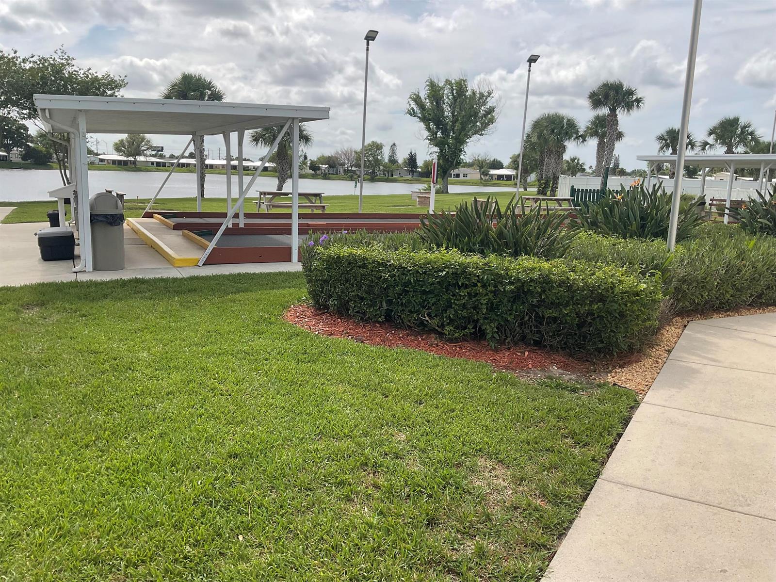 An outdoor shuffleboard court sits under a covered pavilion next to a grassy lawn — 14151 Cisne Circle, Fort Pierce FL 34951, FORT PIERCE, FL