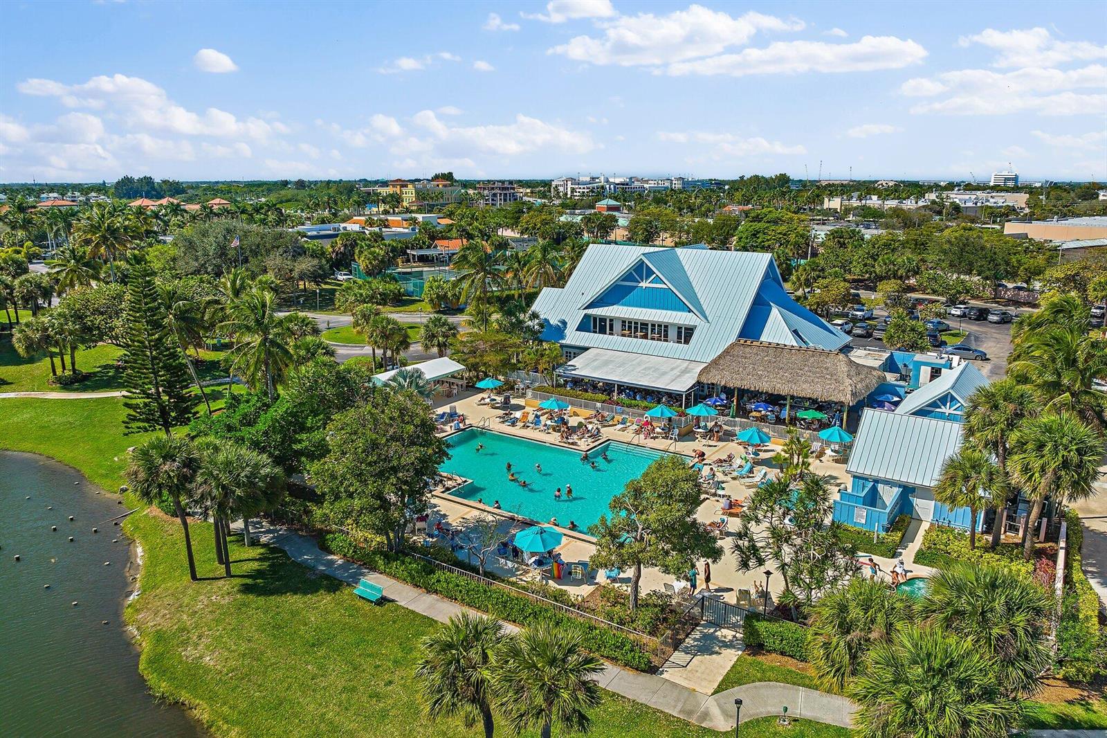 An aerial view of a swimming pool area with a clubhouse and surrounding tropical landscaping — 353 S Us Highway 1 # C203, Jupiter FL 33477, JUPITER, FL