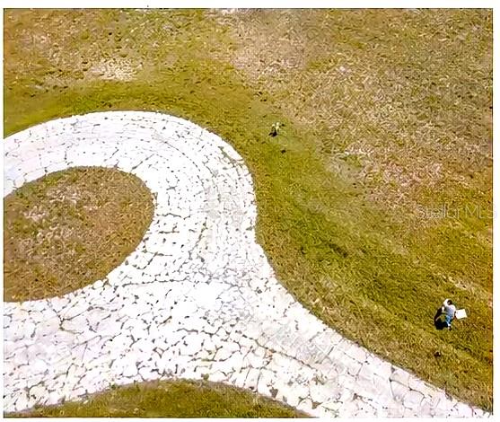 An aerial view shows a curved stone walkway set within a grassy field — 10 PETUNIA COURT, PLACIDA, FL