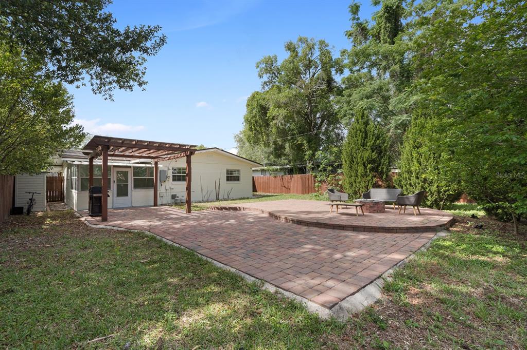 A backyard features a brick paver patio with a wooden pergola and a fire pit area — 1741 WESTCHESTER AVENUE, WINTER PARK, FL