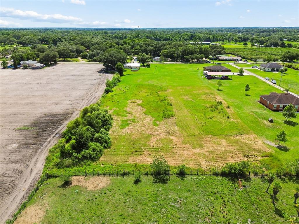 An aerial view shows a large, grassy vacant lot adjacent to a cleared dirt field — 0 KILLEYMOON LANE, DOVER, FL