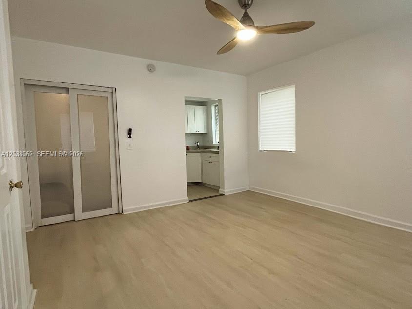 A room with light-colored flooring, a ceiling fan, a sliding door, and a kitchen view — 1027 Euclid Ave # 5, Miami Beach FL 33139, MIAMI BEACH, FL