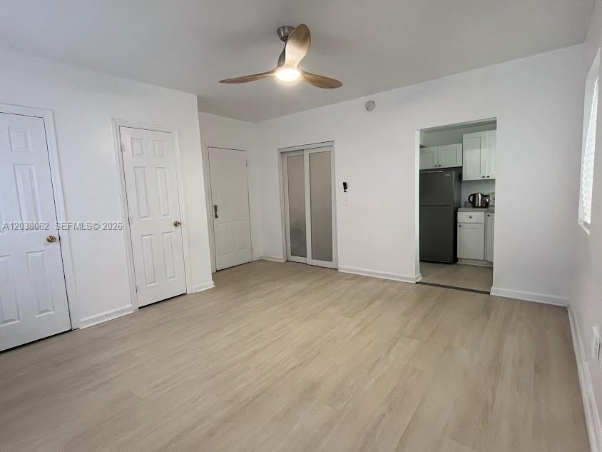 A room with light wood-look flooring, white walls, a ceiling fan, and an adjacent kitchen — 1027 Euclid Ave # 5, Miami Beach FL 33139, MIAMI BEACH, FL