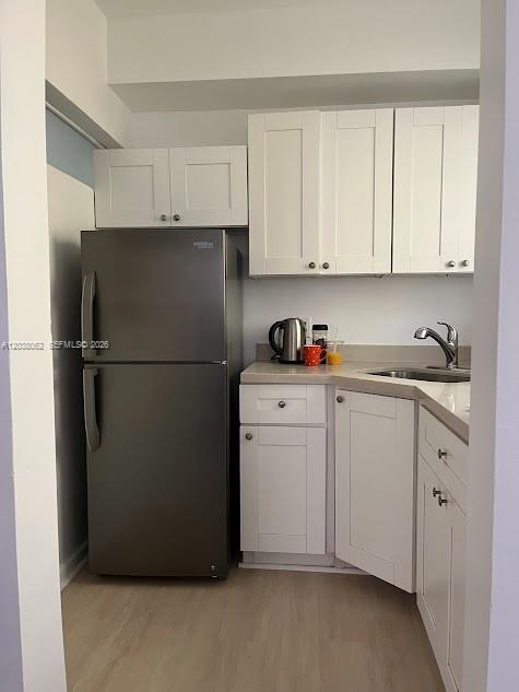 A small kitchen features white cabinets, a stainless steel refrigerator, and light-colored flooring — 1027 Euclid Ave # 5, Miami Beach FL 33139, MIAMI BEACH, FL