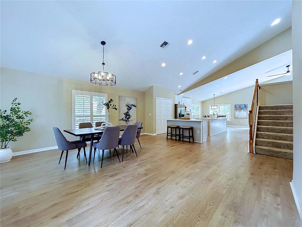 An open-concept dining area and kitchen feature light wood flooring and a staircase — 7703 BRITISH OPEN WAY, LAKEWOOD RANCH, FL