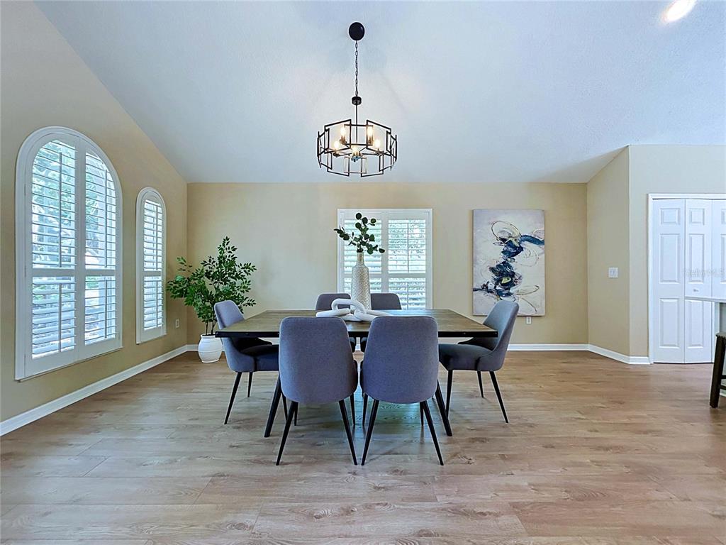 A dining room features a wooden table, six gray chairs, a chandelier, and arched windows — 7703 BRITISH OPEN WAY, LAKEWOOD RANCH, FL