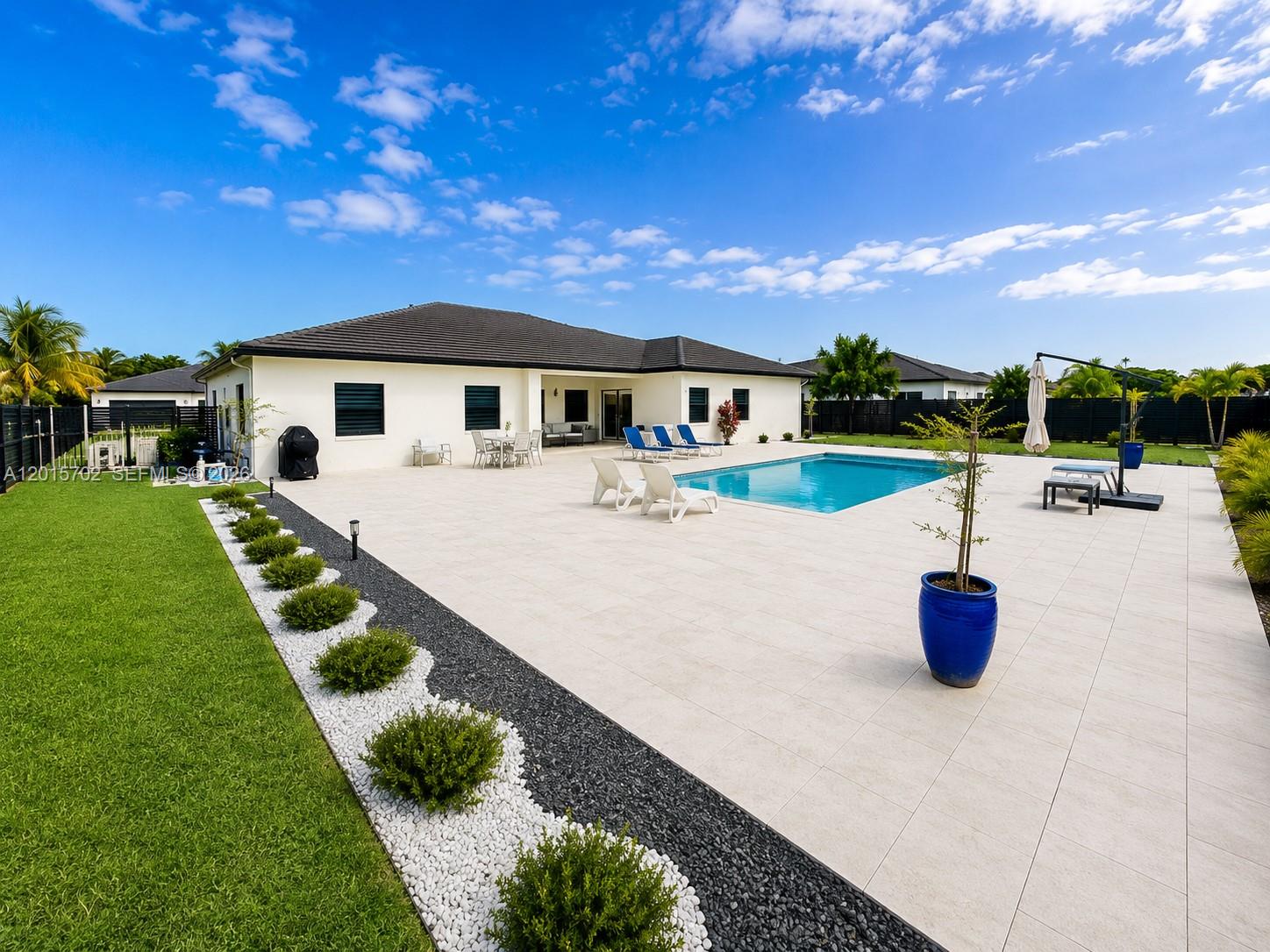 A backyard features a swimming pool, a paved patio, and a landscaped garden border — 21480 SW 132nd Ct, Miami FL 33177, MIAMI, FL