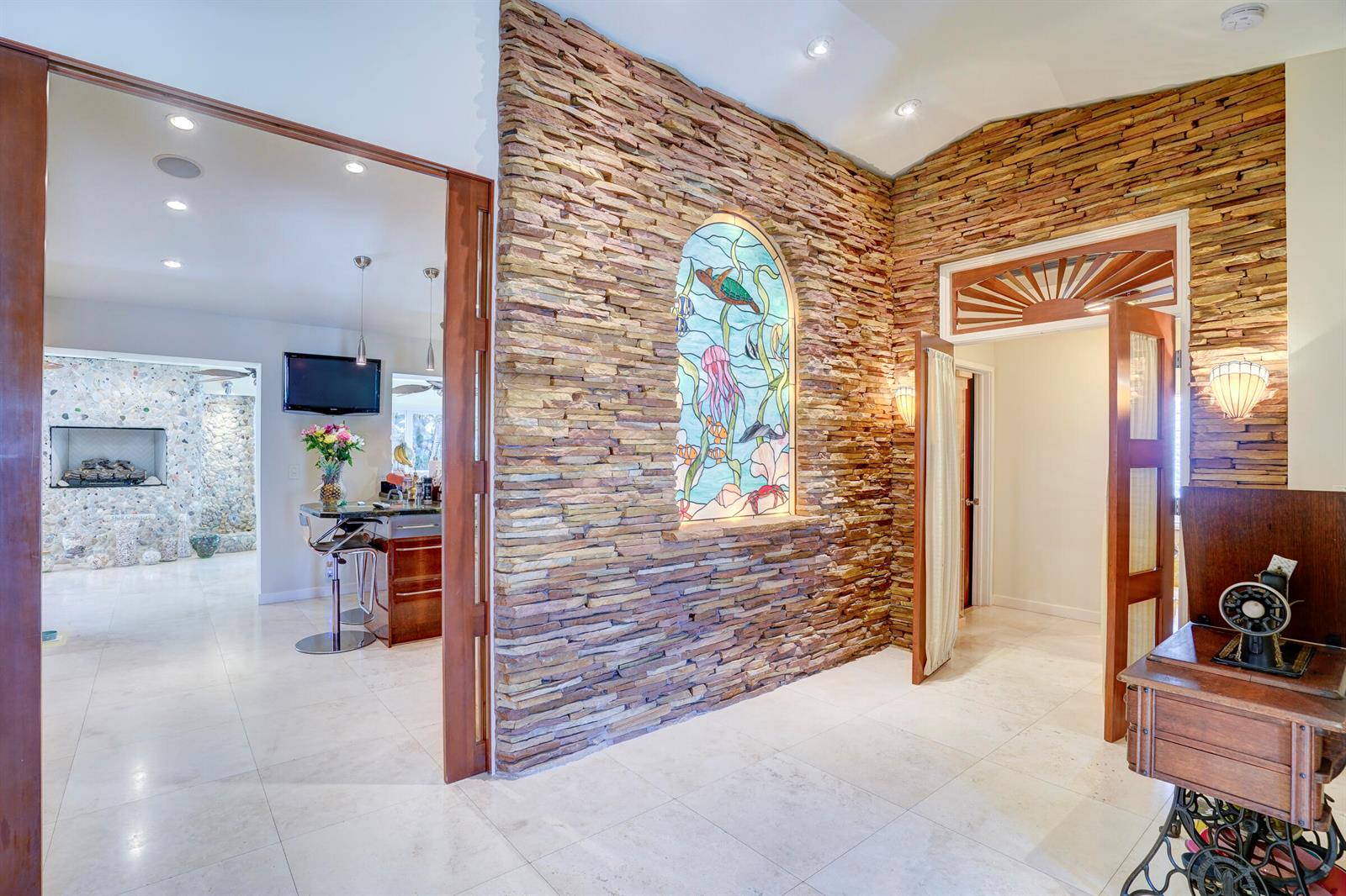 A stone accent wall features a stained glass window in a room with tile flooring — 1191 Emerald Lane, Singer Island FL 33404, SINGER ISLAND, FL