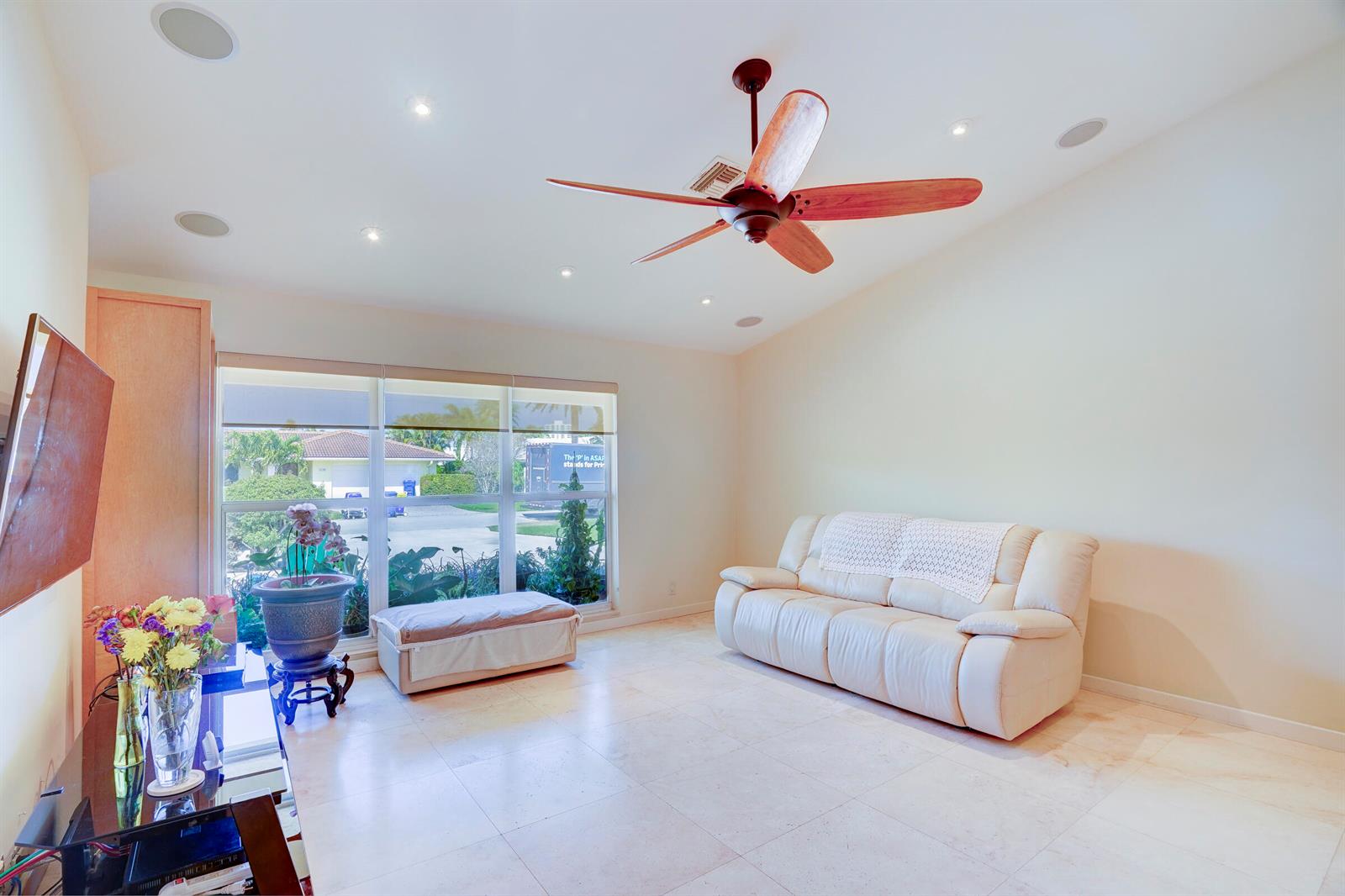 A living room features a white leather sofa, a ceiling fan, and large windows — 1191 Emerald Lane, Singer Island FL 33404, SINGER ISLAND, FL
