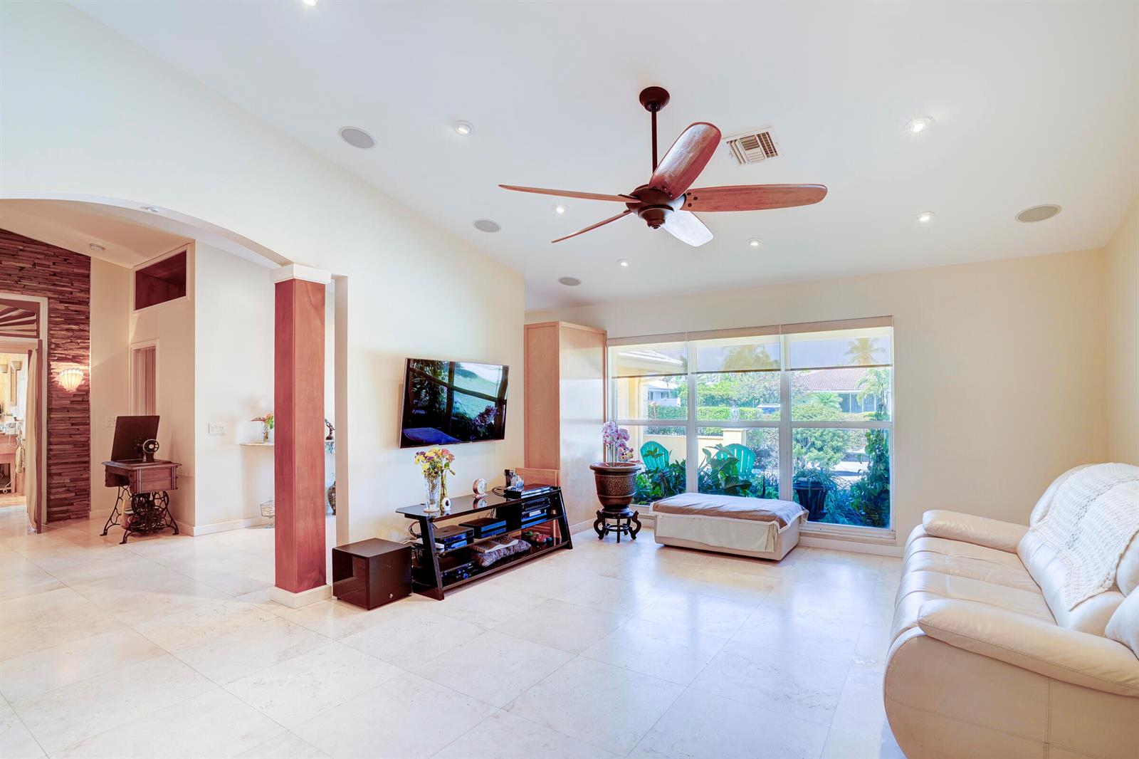 A living room features a ceiling fan, tiled floors, a television, and large windows — 1191 Emerald Lane, Singer Island FL 33404, SINGER ISLAND, FL