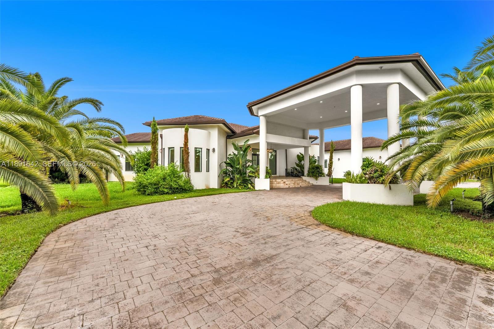 A white house with a large porte-cochère and a paved driveway surrounded by palm trees — 12175 SW 45th St, Miami FL 33175, MIAMI, FL