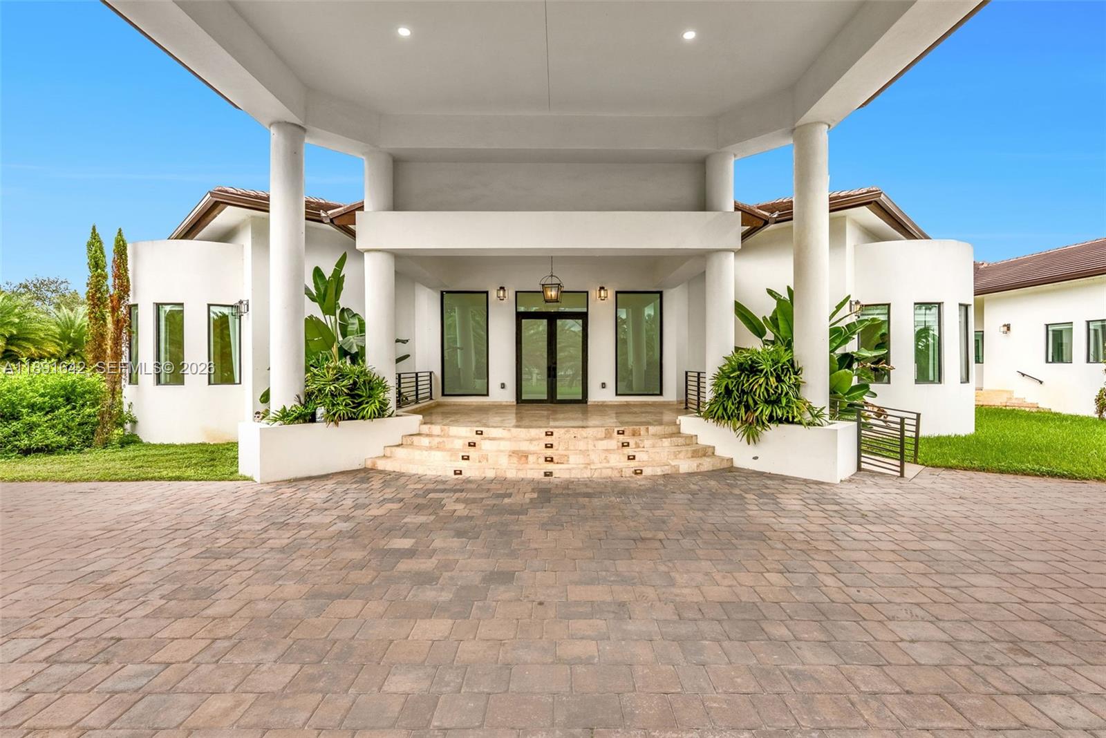 A large white house with a covered entryway, stone steps, and a paved driveway — 12175 SW 45th St, Miami FL 33175, MIAMI, FL