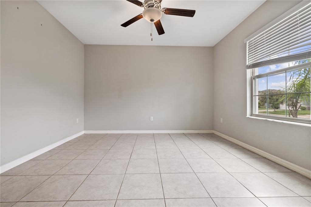 An empty room with light gray walls, tile flooring, a ceiling fan, and a window — 9413 CHANNING HILL DRIVE, RUSKIN, FL