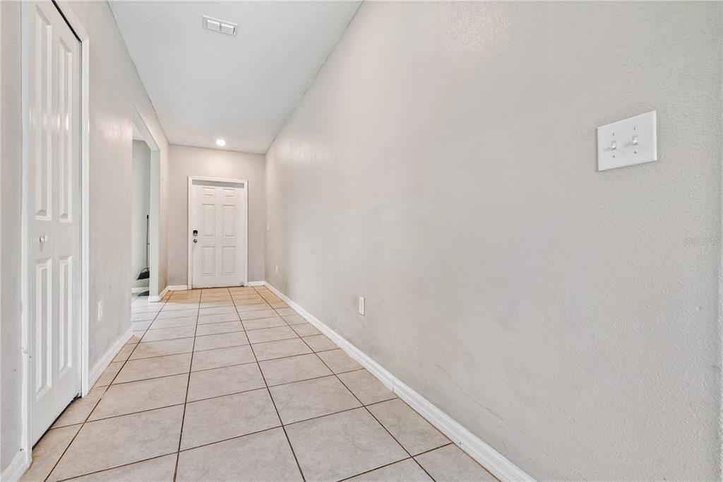 A hallway with light-colored tile flooring, white walls, a white door, and a closet — 9413 CHANNING HILL DRIVE, RUSKIN, FL
